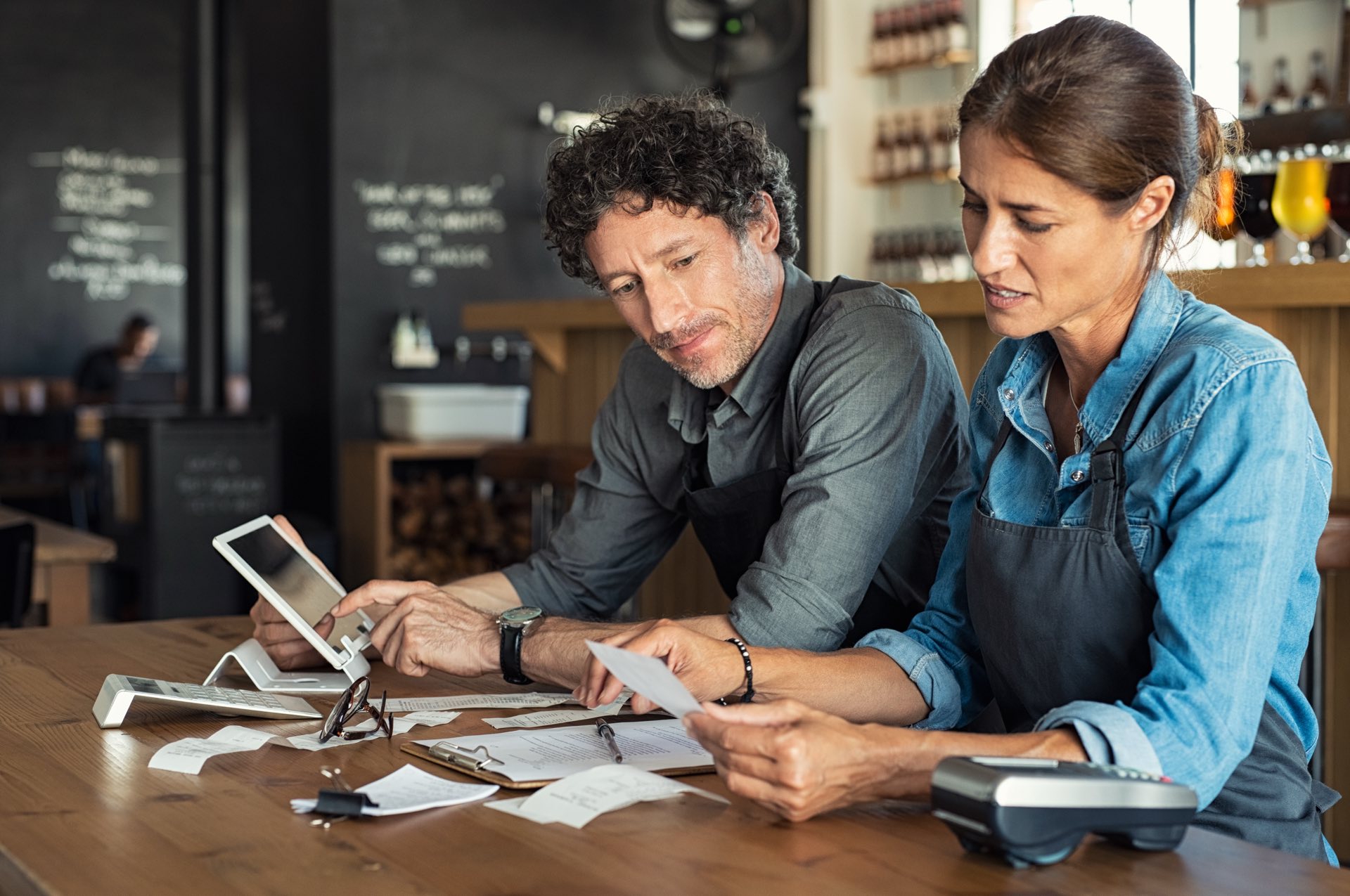 Man and woman sitting at a desk on an ipad and looking over paperwork