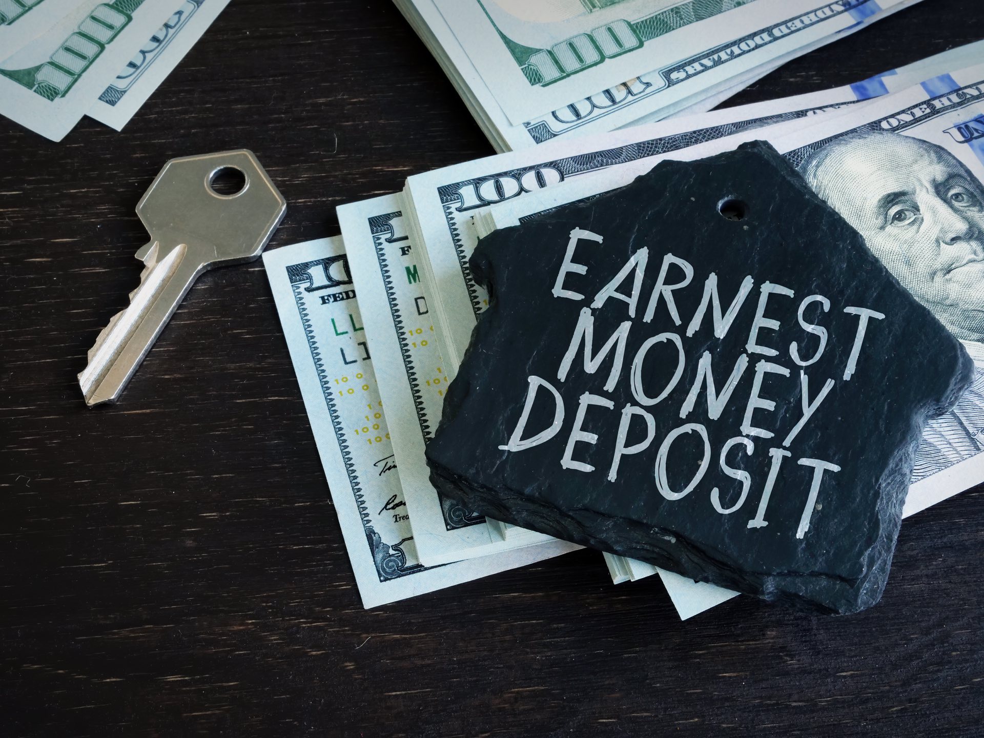 A label that says earnest money deposit on top of a stack of money