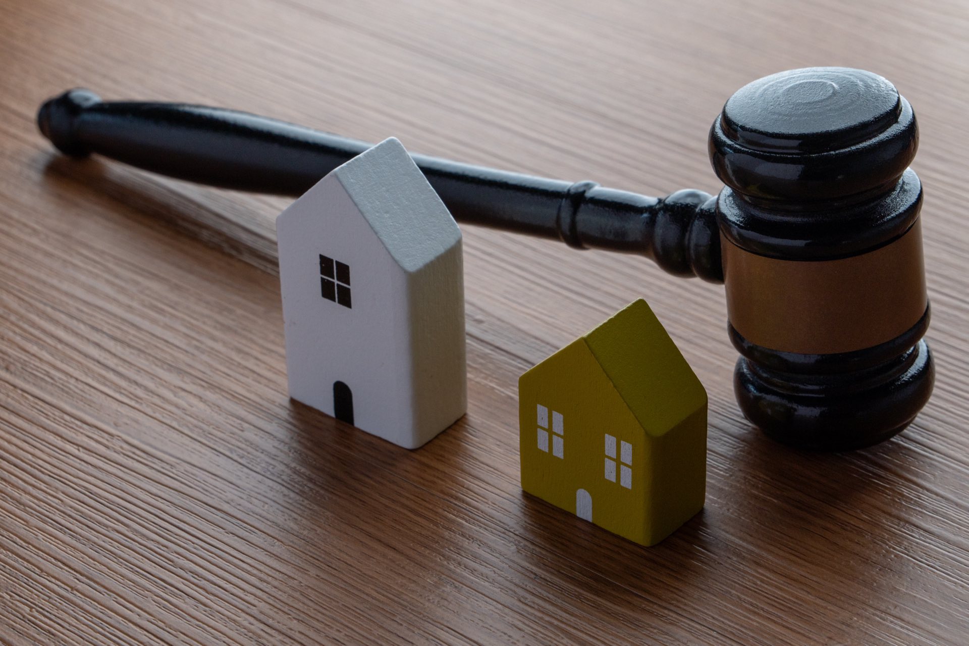 Two small wooden houses and a gavel on a desk
