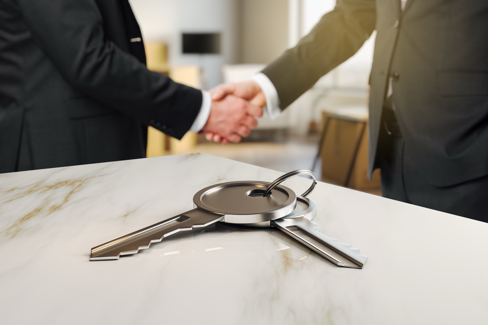 Close up of keys on a marble table with a handshake in the background