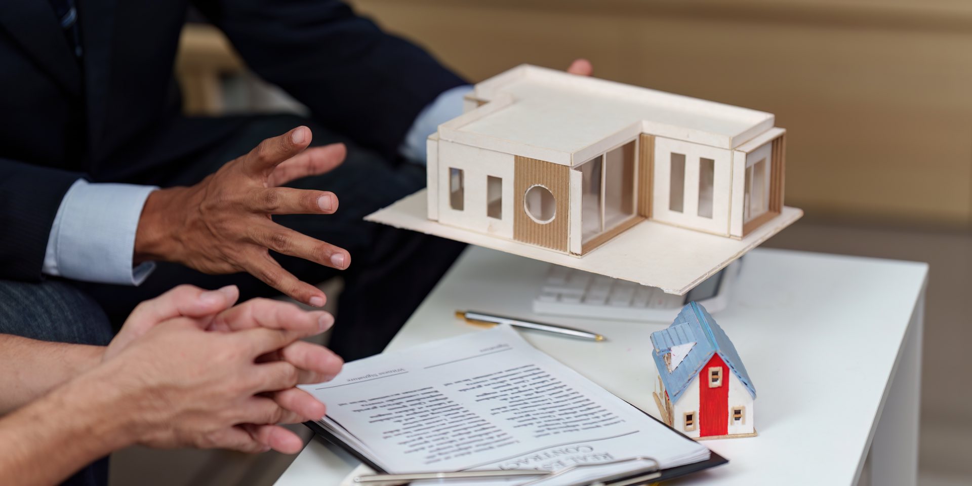 Two people sitting at a desk going over paperwork and holding a model commercial building