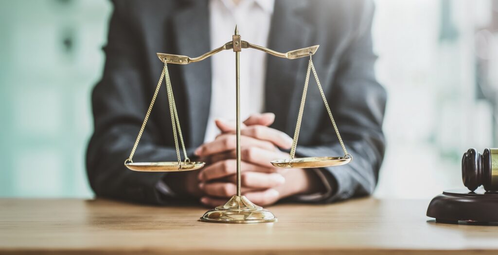A lawyer with scales of justice on a desk | Wallach & Associates, P.C.